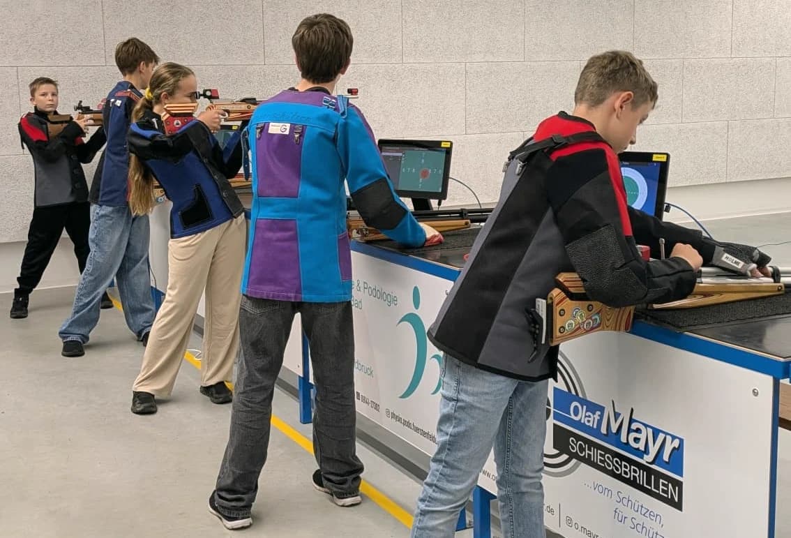 Fünf Jugendliche in bunten Schützenjacken beim Training an den elektronischen Ständen